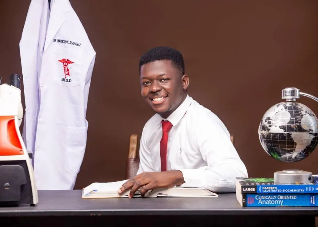 An alumnus at a desk with medical textbooks
